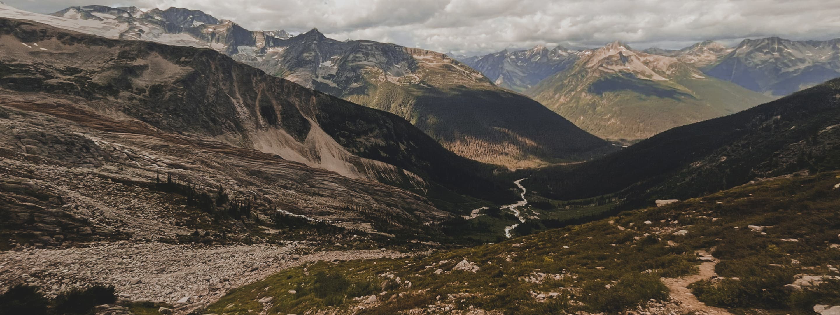 Rocky terrain leads to distant peaks and a snaking river.